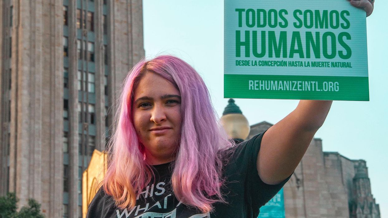 Woman holding 'We Are All Humans' sign