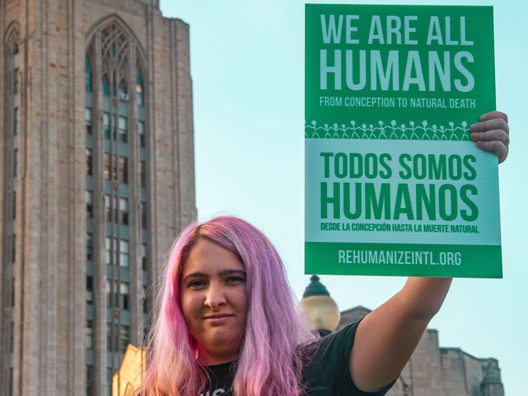 Woman holding 'We Are All Humans' sign