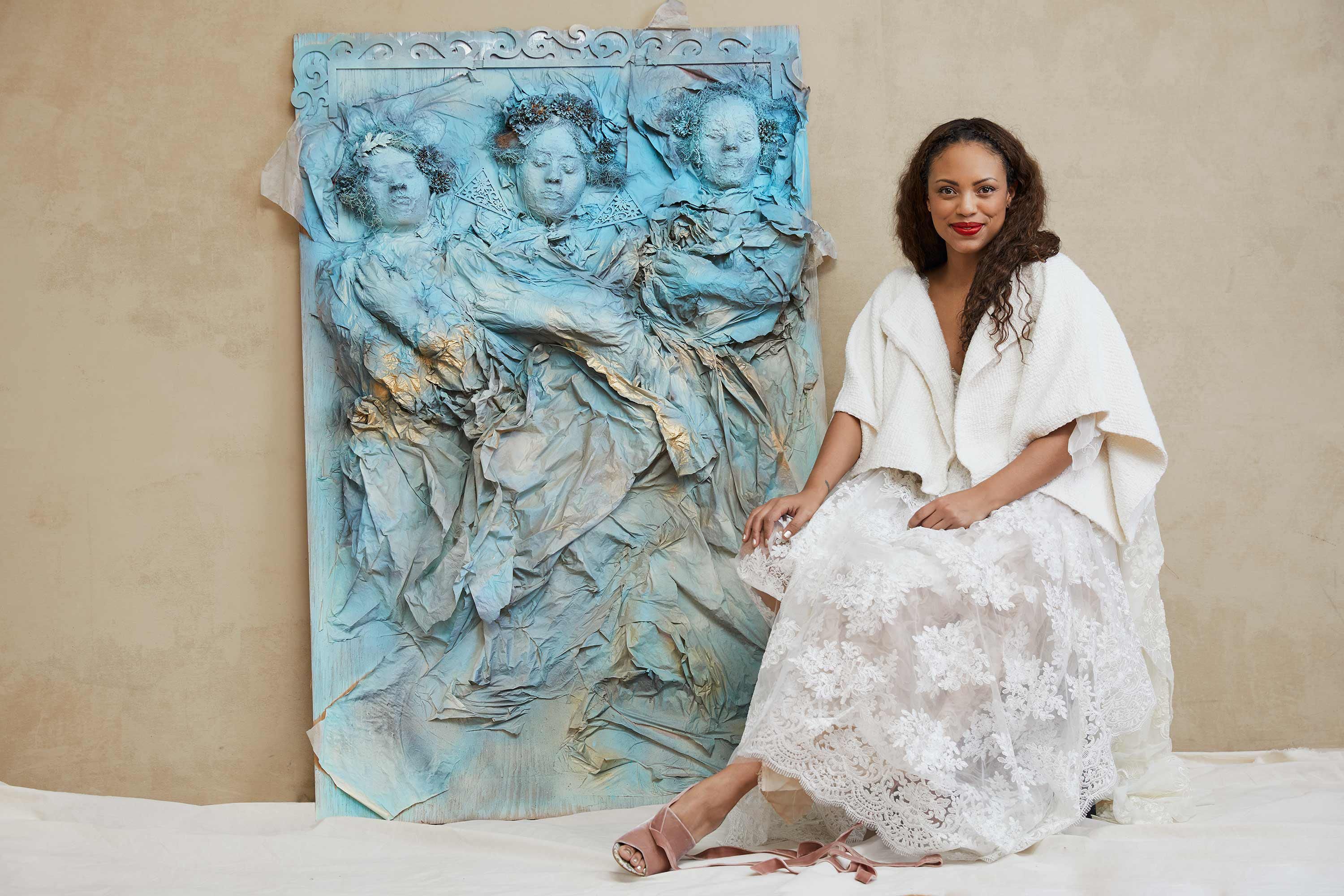 The artist Jaime Lee Kirchner of the show Bull sits next to her three dimensional painting The Three Belles.