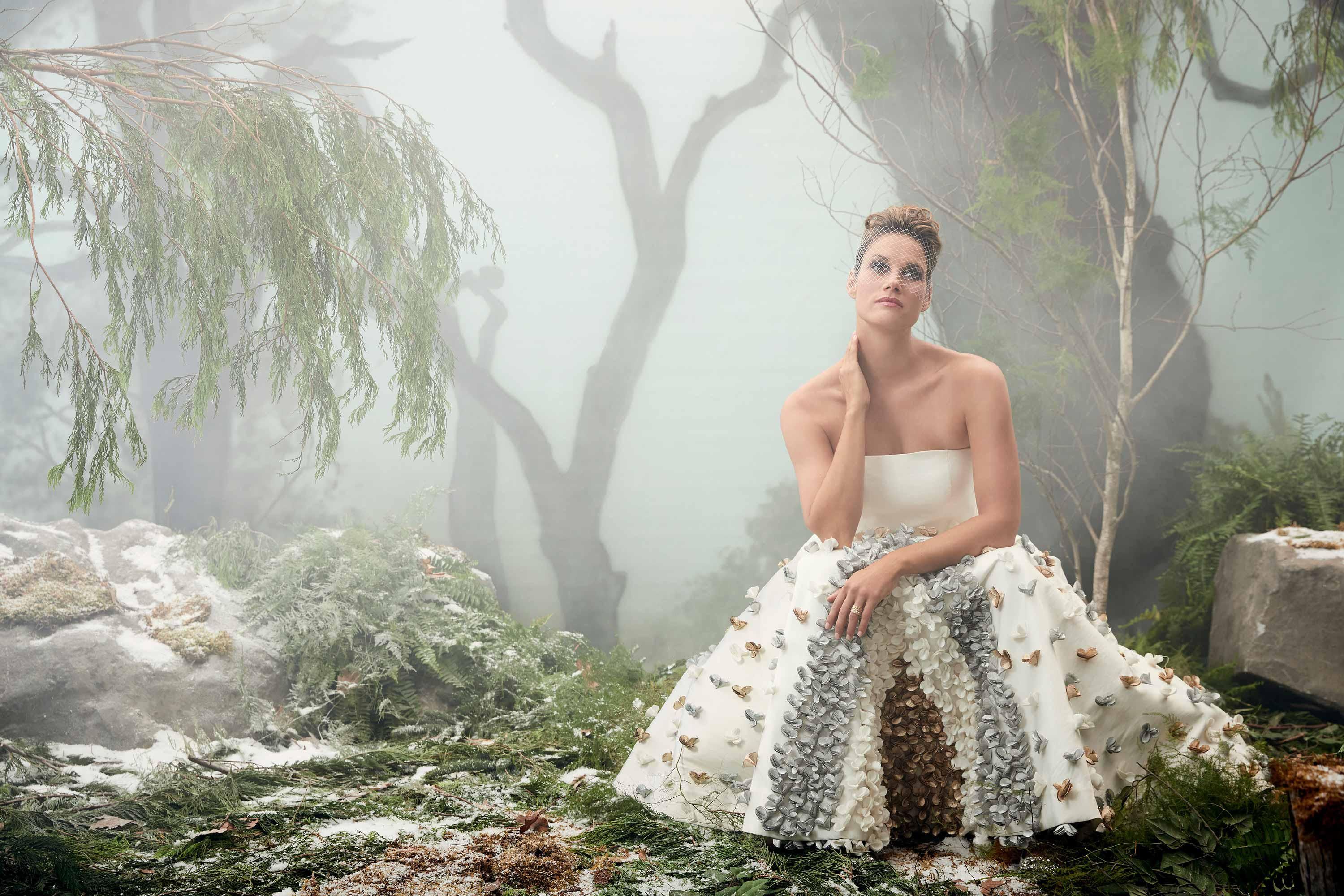 Missy Peregrym poses in a forest setting wearing a strapless white gown with flowers