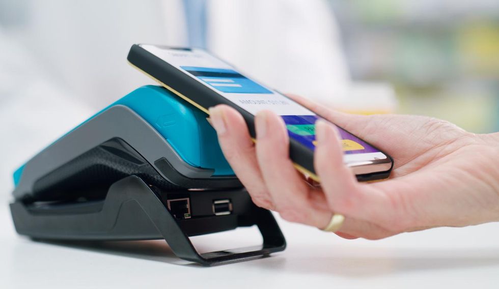 a photo of a smartphone connecting with a credit card machine via NFC connetion.