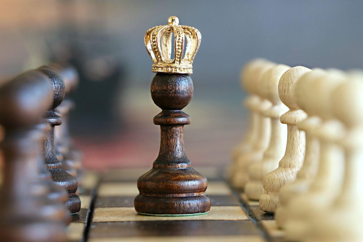 pawn in the middle of a chess board with a crown on top