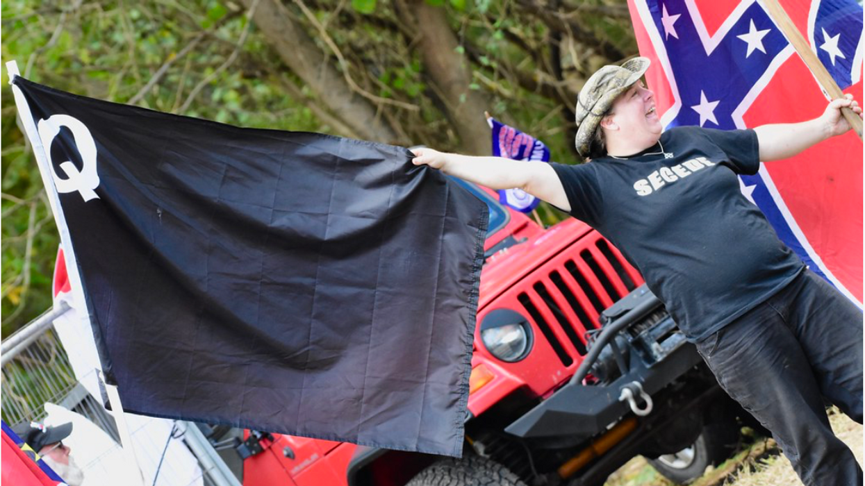 Qanon supporter with hand on a flag representing the far-right group. 