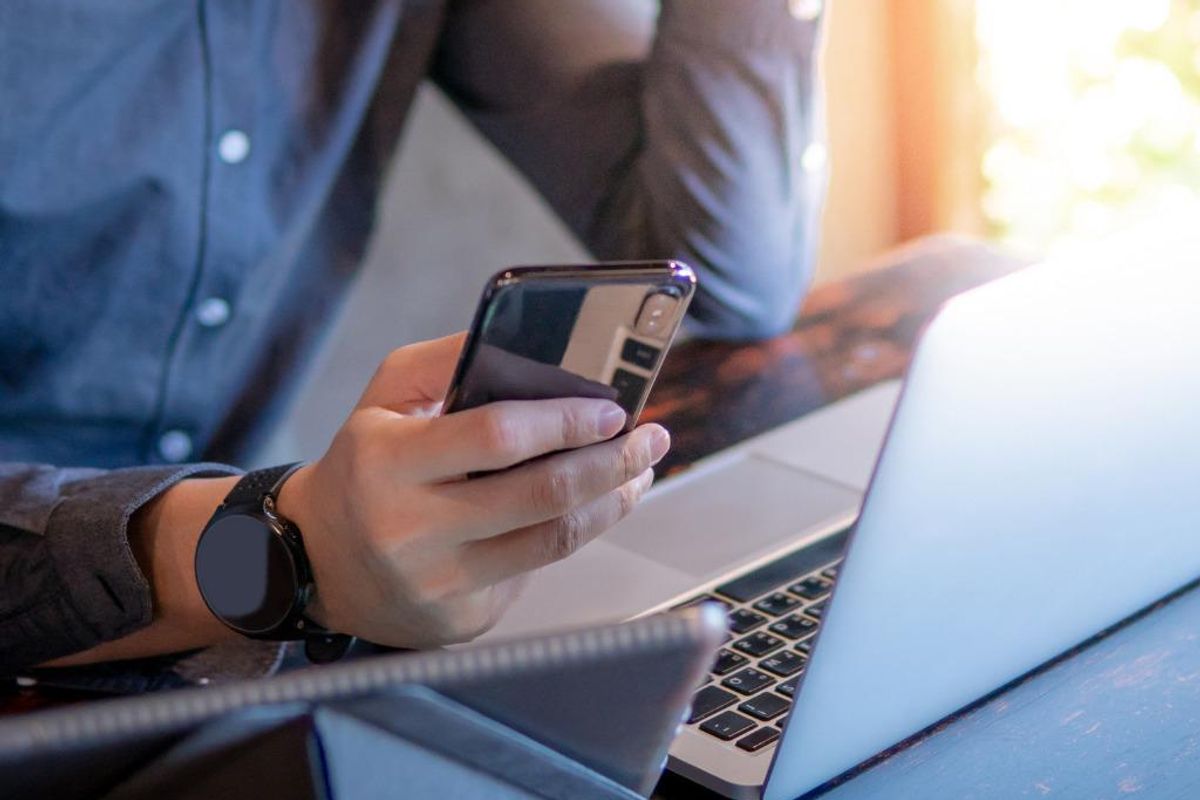 Man holding a smartphone over a computer