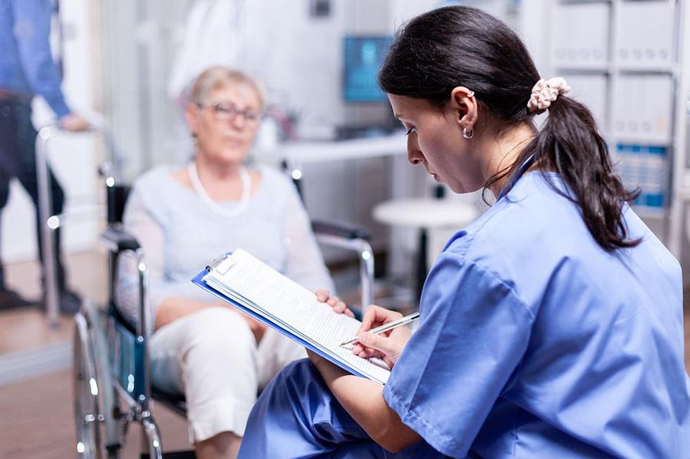 Medical assistant writes down some notes while talking to a patient