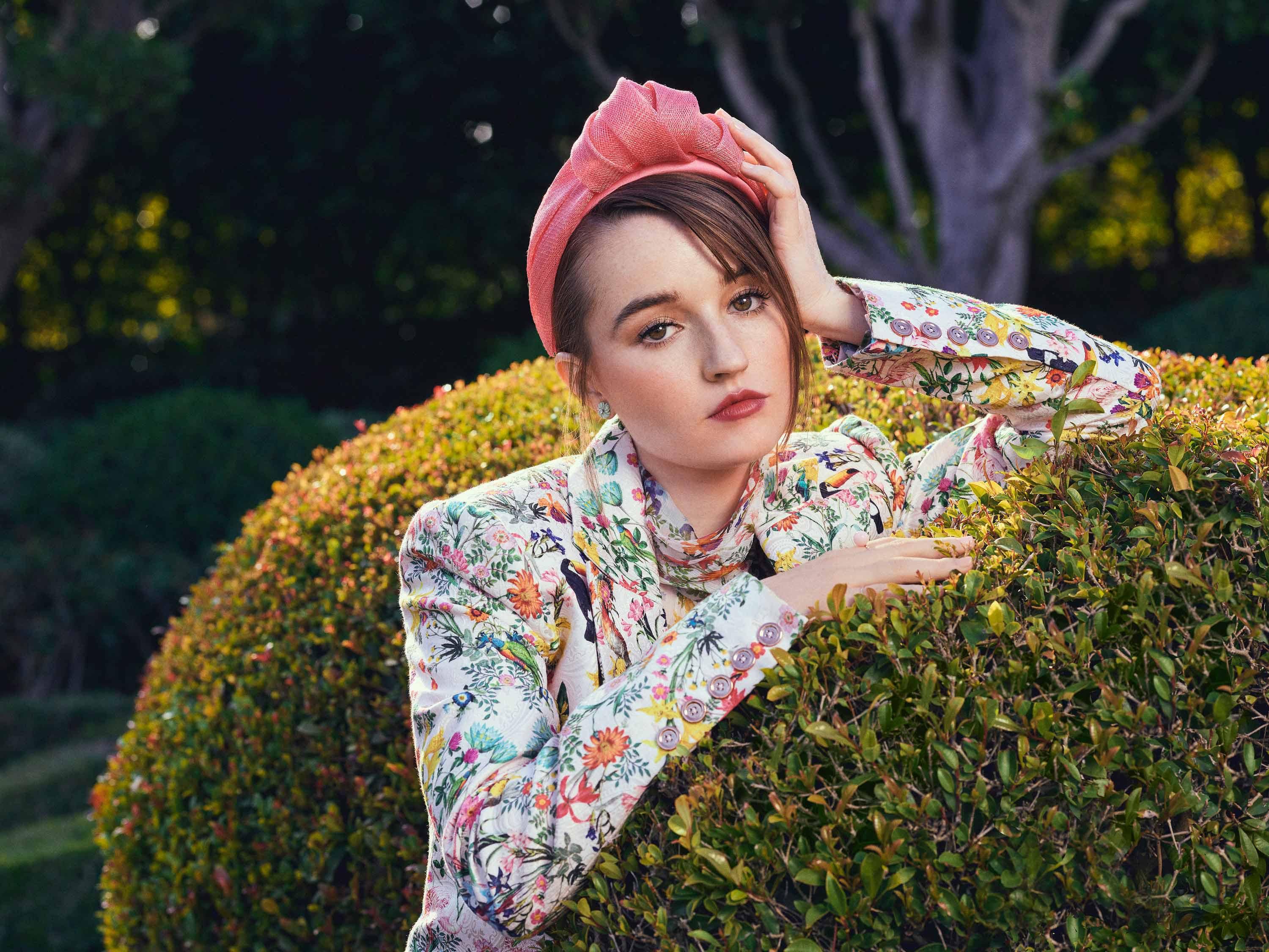 Kaitlyn Dever wears a floral jacket during a garden photo shoot