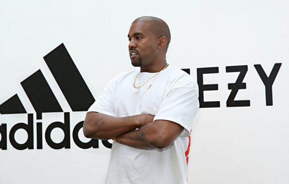 Kanye West arms folded in front of the adidas and yeezy logos