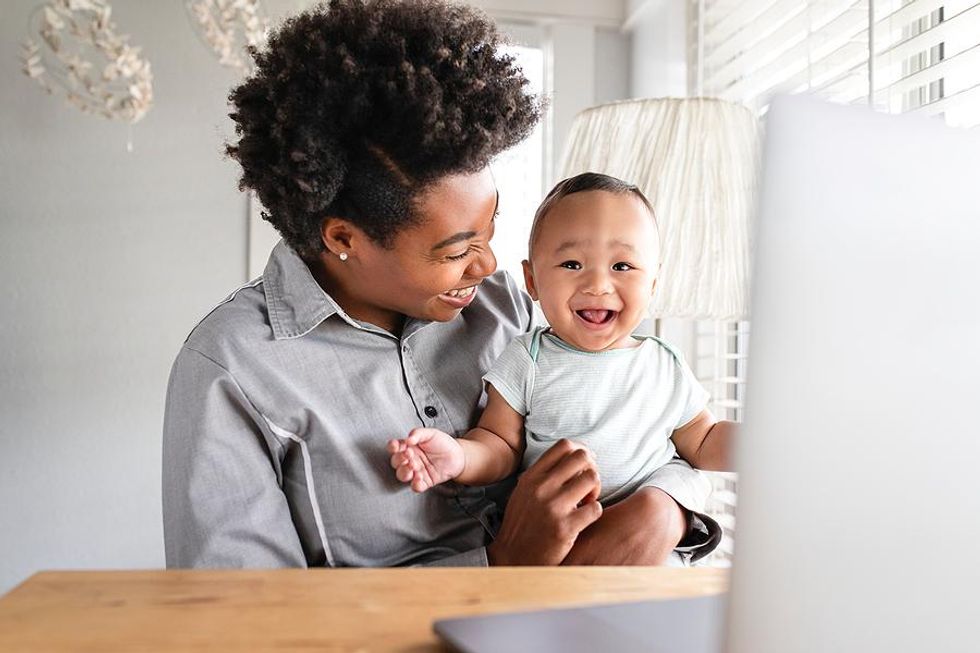 Working mom holds her baby while on a flexible work schedule