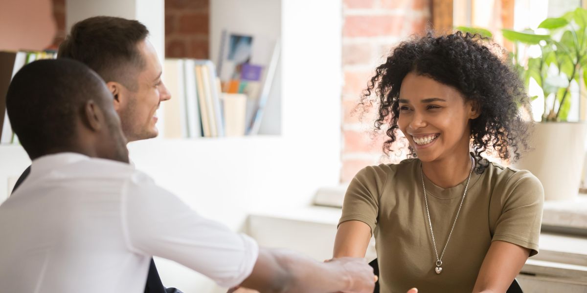 black woman with natural curly hair shakes hands with black man as man smiles in an interview