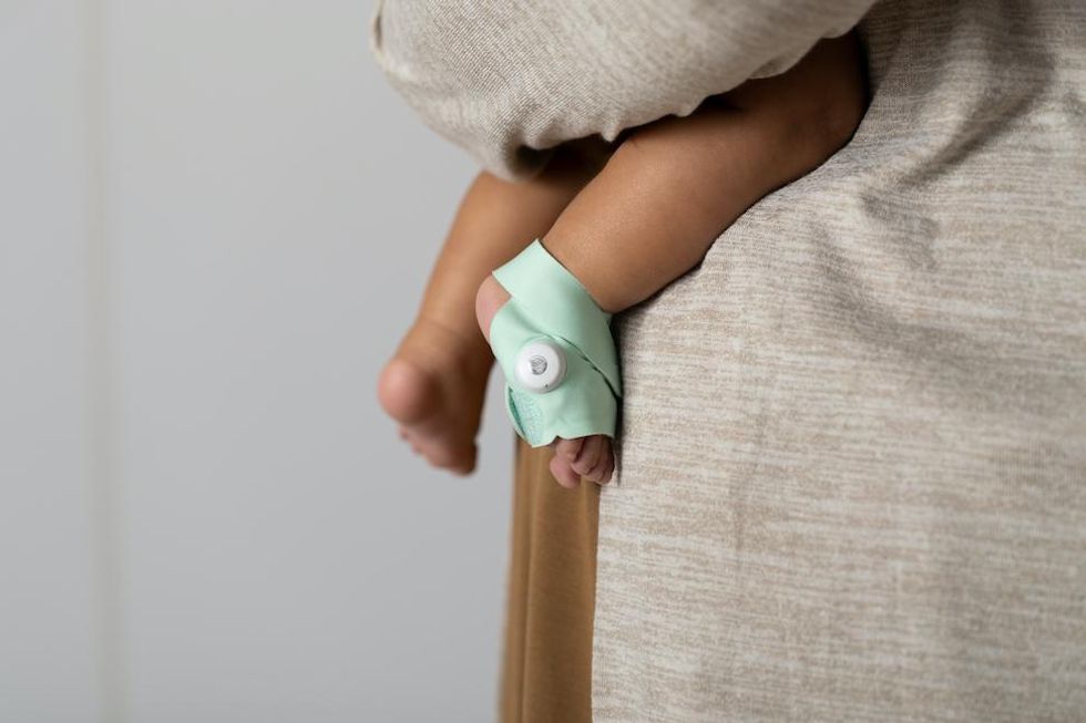 a photo of baby wearing Owlet Smart Sock in the arms of a parent