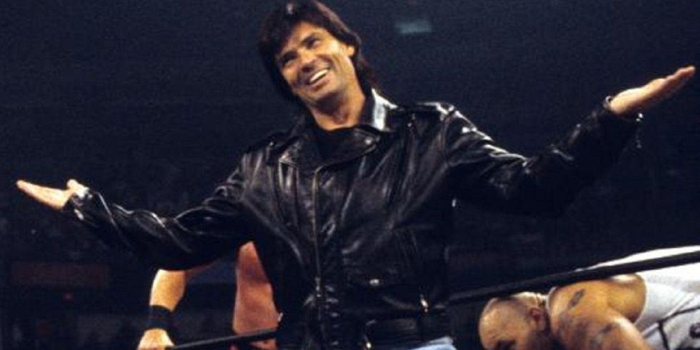 Eric Bischoff smiling in the ring with his arms extended
