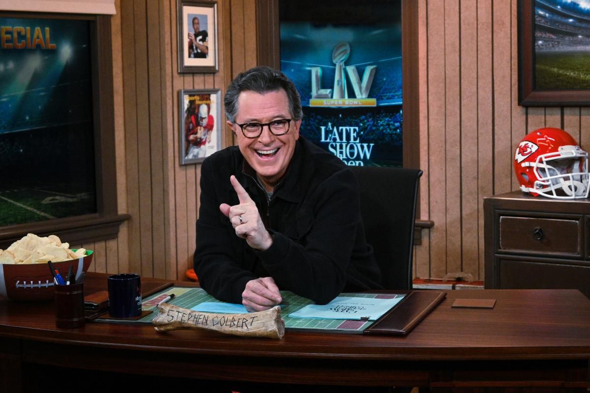 Stephen Colbert sitting at his desk and smiling