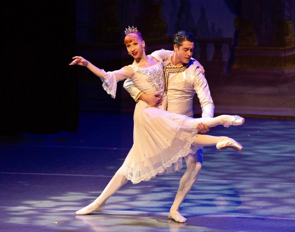 Mary Grace Koznarek, wearing a delicate pink chiffon gown and sparkly tiara, wraps her left arm around Timothy O'Donnell's right shoulder and lifts both legs as if sitting, while he holds her right calf and lunges on his left leg.