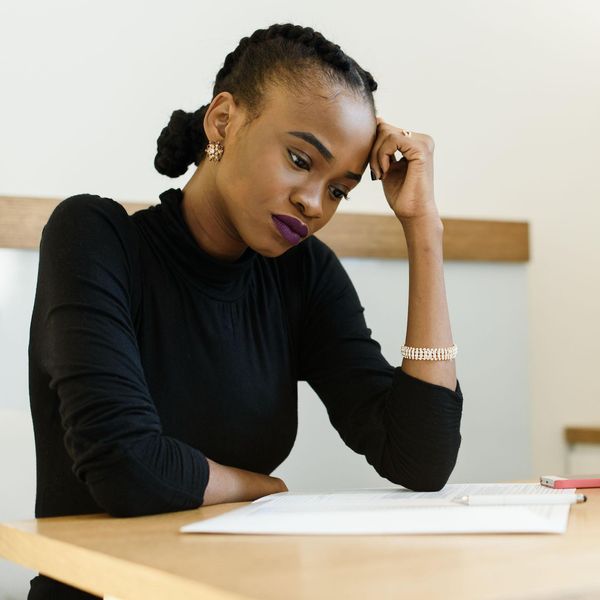 African-American woman in black shirt sitting at wooden desk in fustration