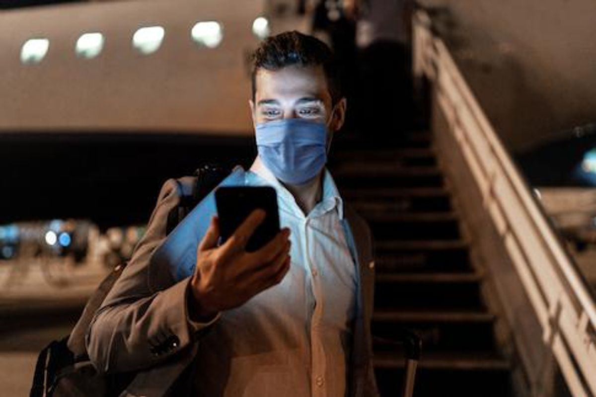 A man traveling on an airplane while wearing a mask