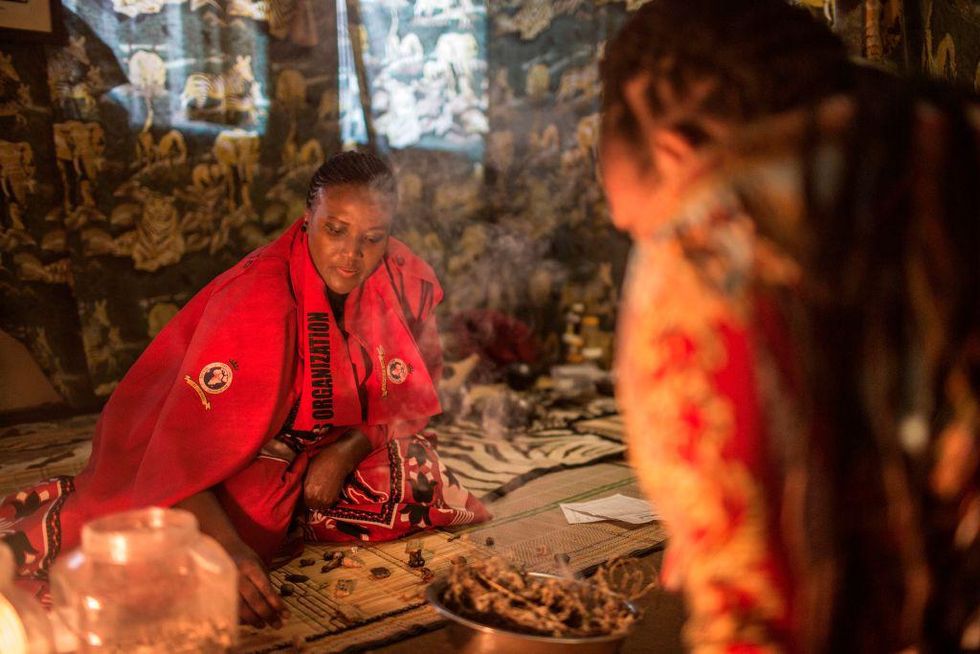 A traditional healer dressed in red and black traditional gear.