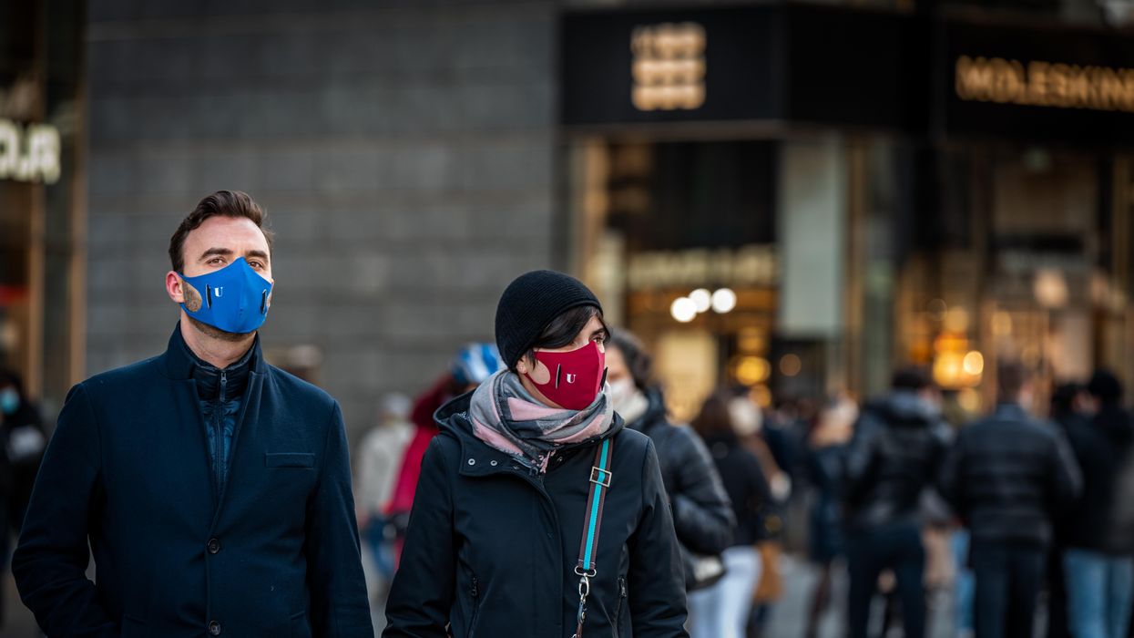 Masked people walking around a city.
