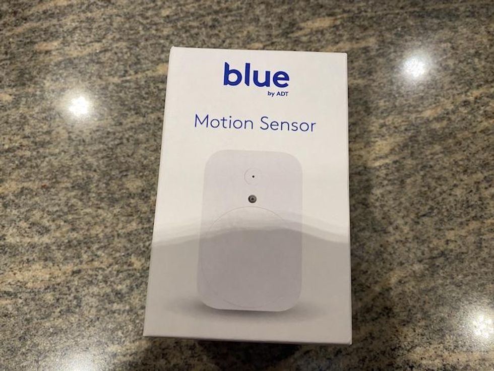 Blue by ADT Motion Sensor on a counter in a box.