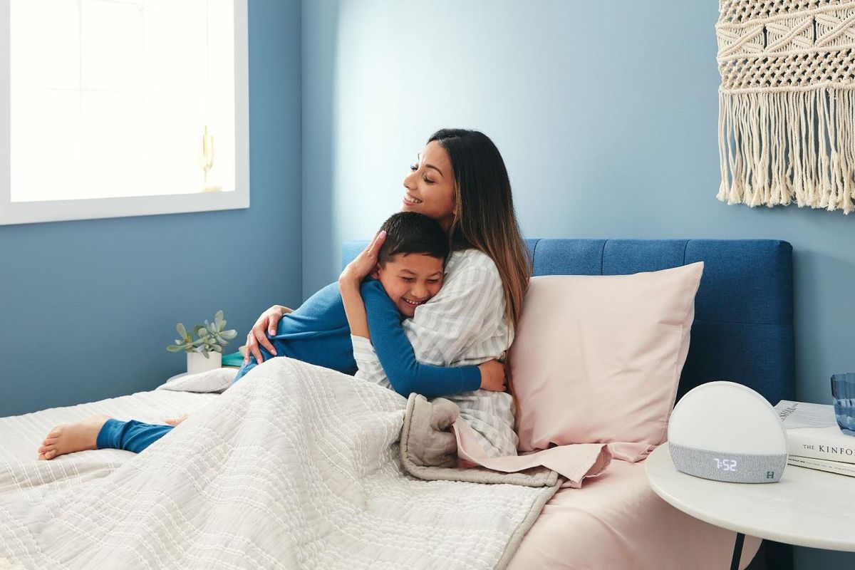woman in bed hugging her son with hatch on her nightstand 