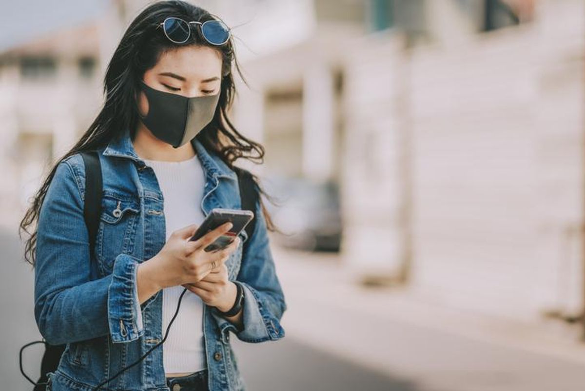 A woman with a smartphone wearing a mask