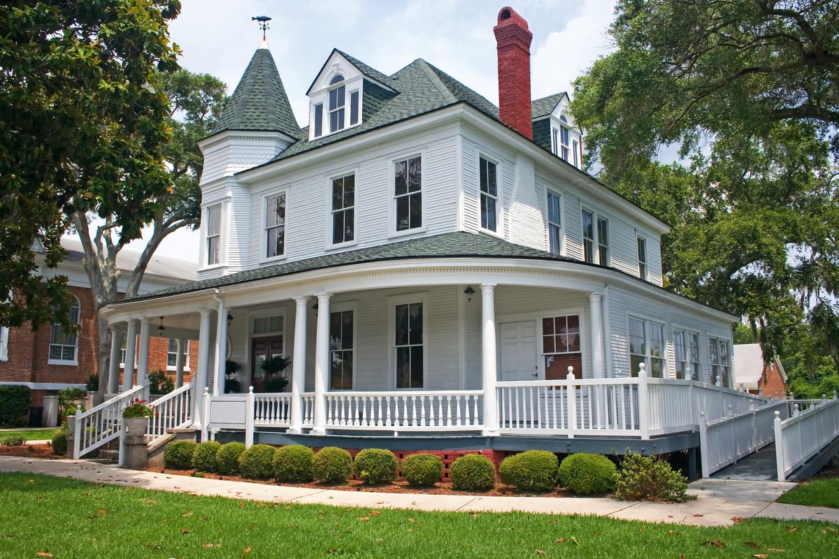 Large house with wrap-around porch and green lawn