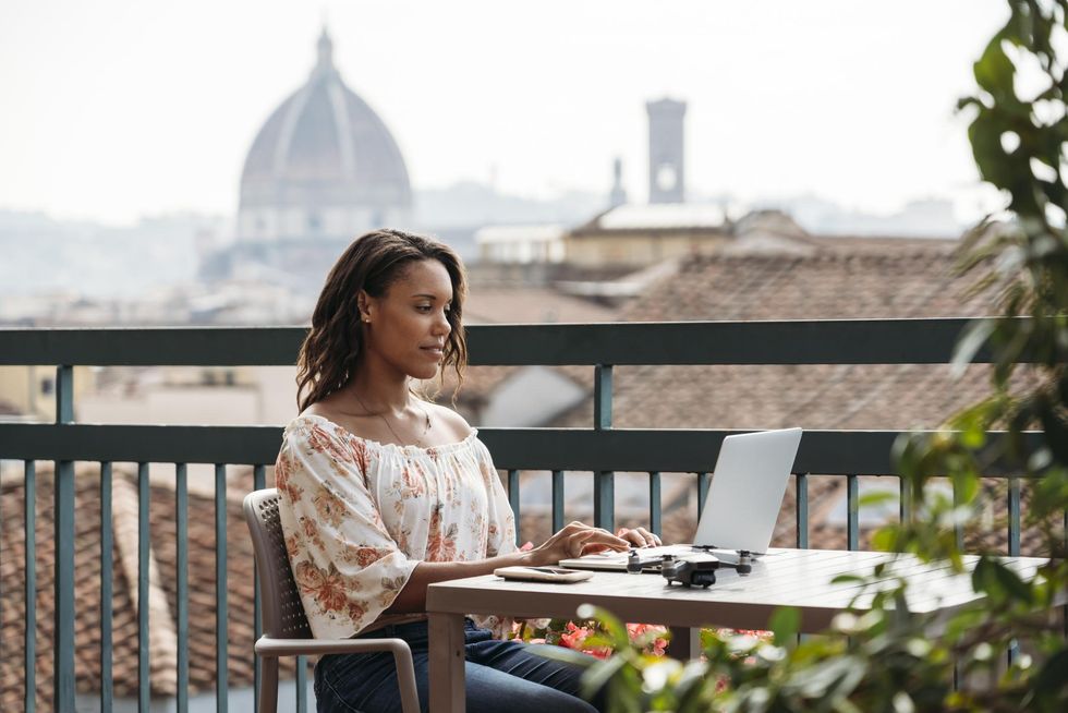 black-woman-typing-computer-balcony-in-italy