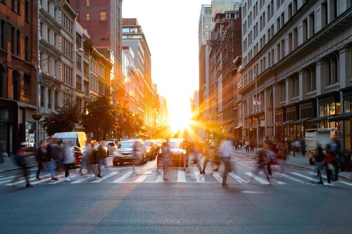 People commuting on a busy city street as the sunsets