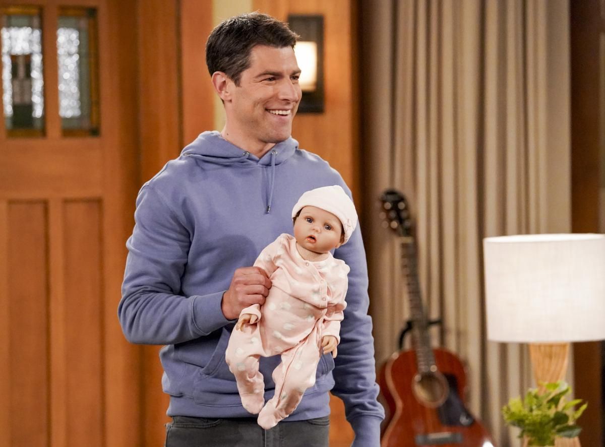 Max Greenfield carrying a baby doll