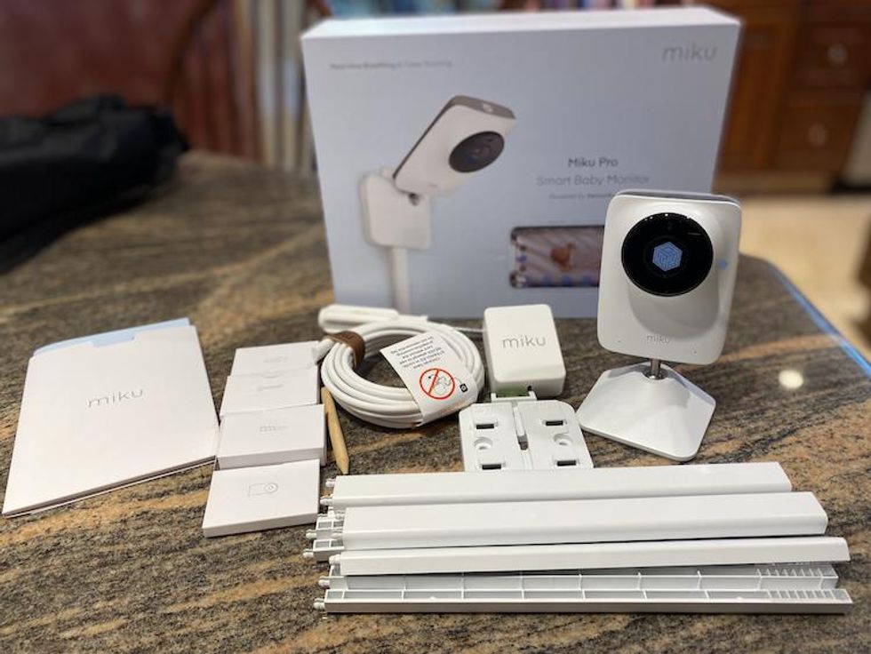 Miku Pro Smart Baby Monitor and wall mount unboxed on a counter.