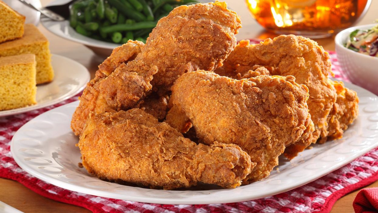 Plate of fried chicken beside cornbread, green beans, sweet tea