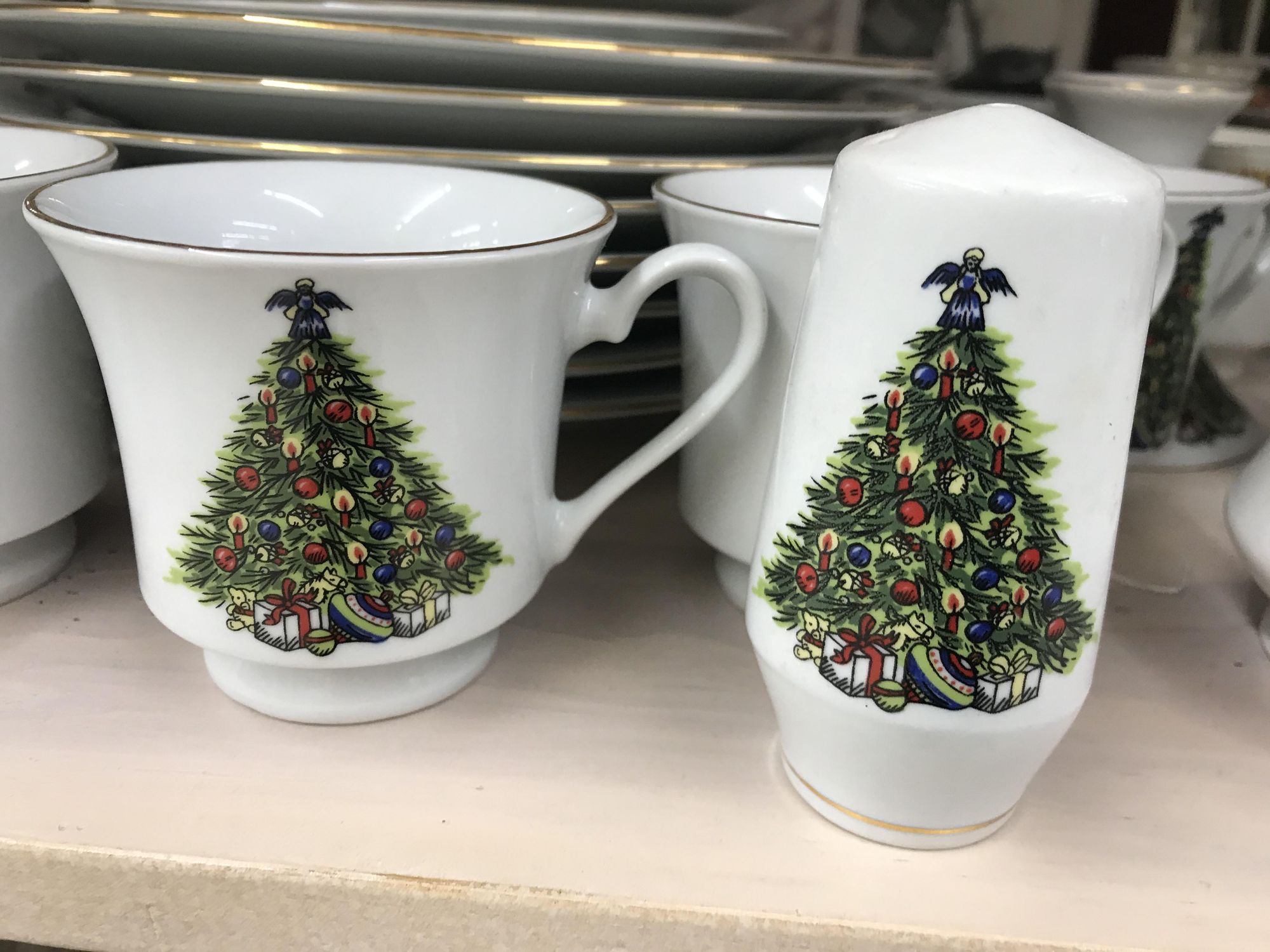 White coffee mug and salt shaker with Christmas trees on it.