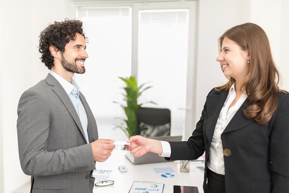 Man gives a woman his business card at a job fair