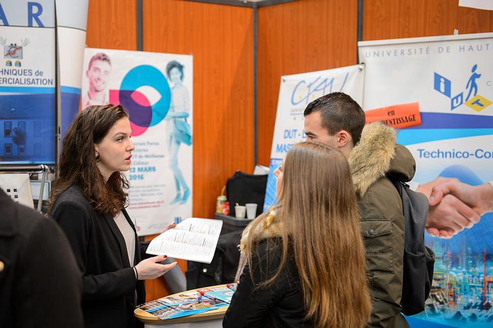 Job seekers ask an employer a question at a job fair