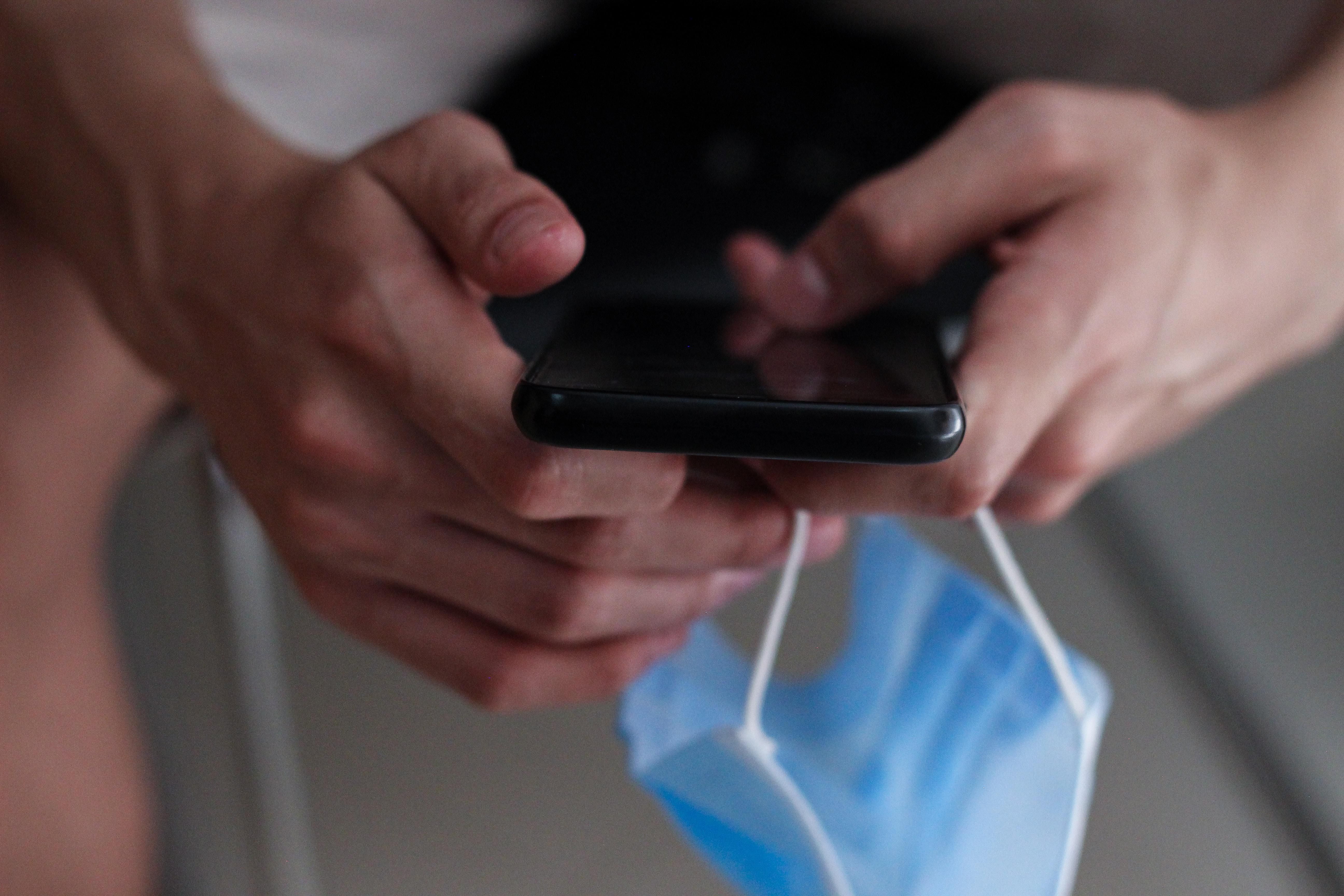 Person on phone holding a mask