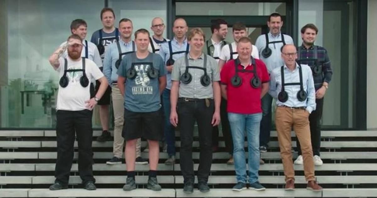 group of men wearing "breast weights" pose for group picture on steps.
