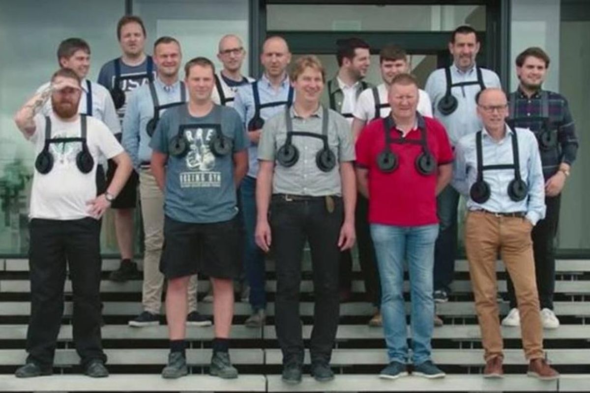 group of men wearing "breast weights" pose for group picture on steps.