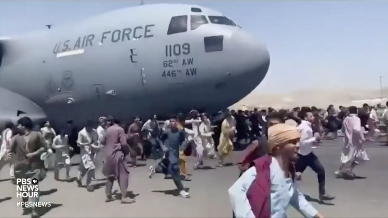 Afghans run on the tarmac of Kabul's airport in a desperate attempt to flee the country.
