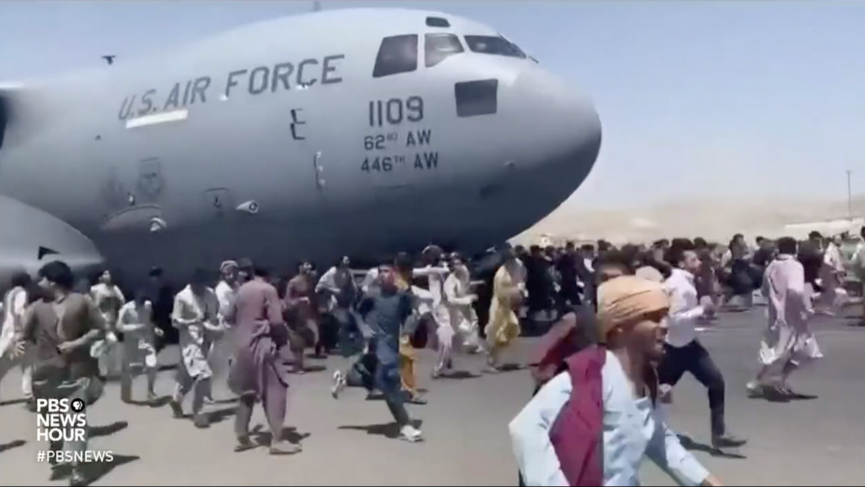 Afghans run on the tarmac of Kabul's airport in a desperate attempt to flee the country. 