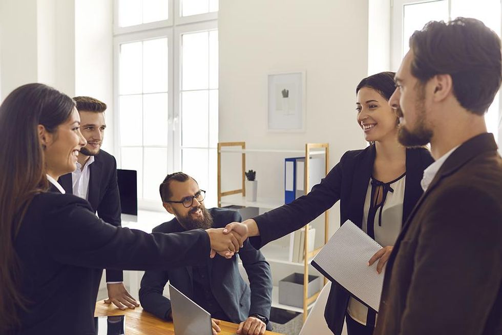 Woman shakes hands with coworkers at her new job