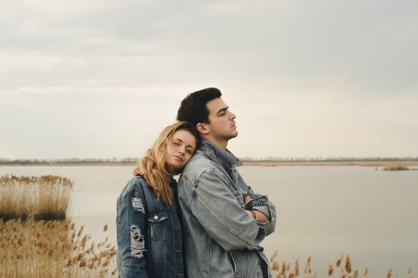 woman leans head on man's shoulder as he faces away