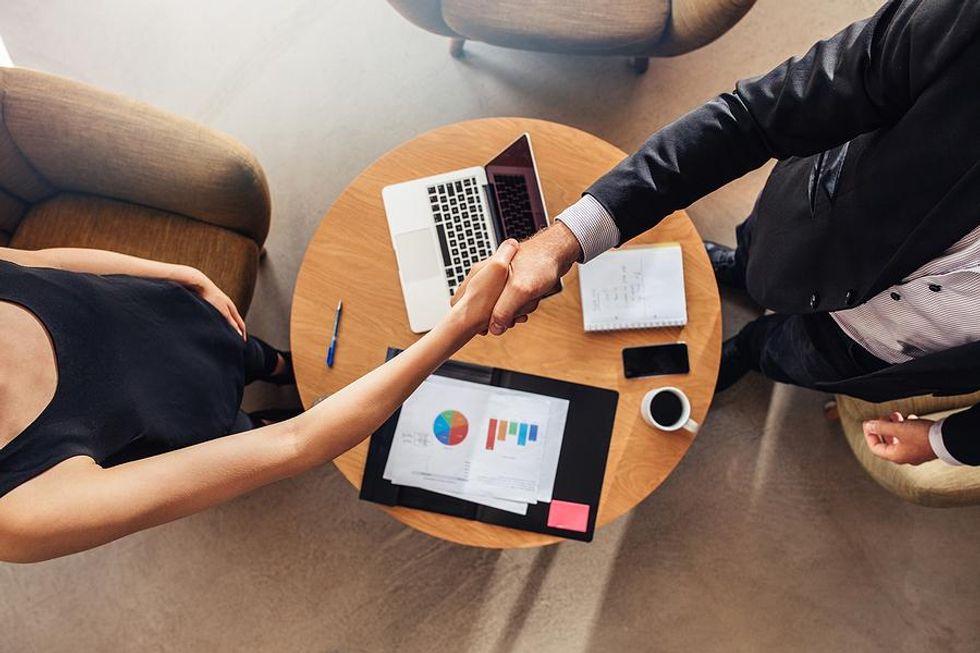 Woman shakes hands with her manager during a performance review