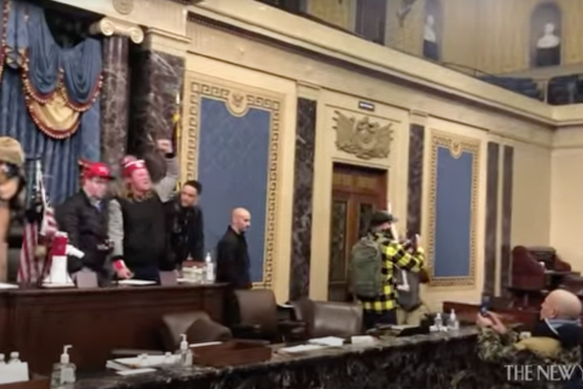 January 6 image featuring QAnon Shaman and men in red hats trying to take over Congress