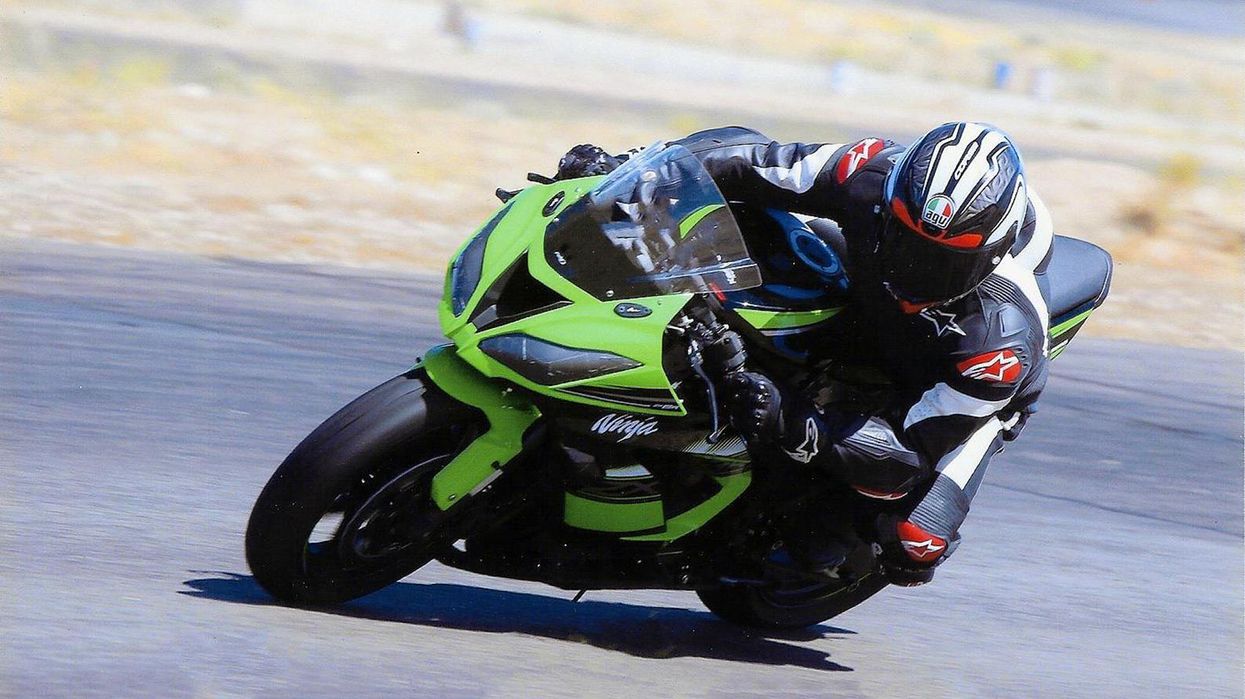 Actor Tim Kang rides a motocycle on a track and leans deeply into a turn