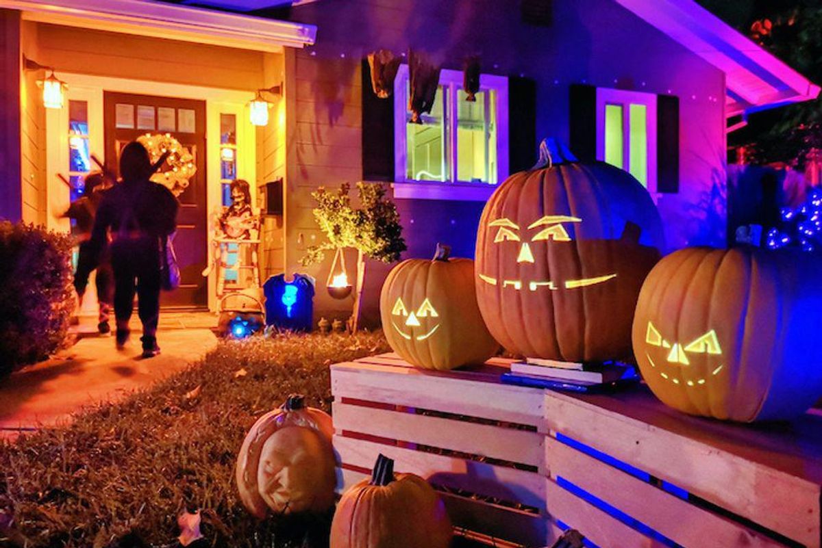 Trick or treaters going to a front door on Halloween night.