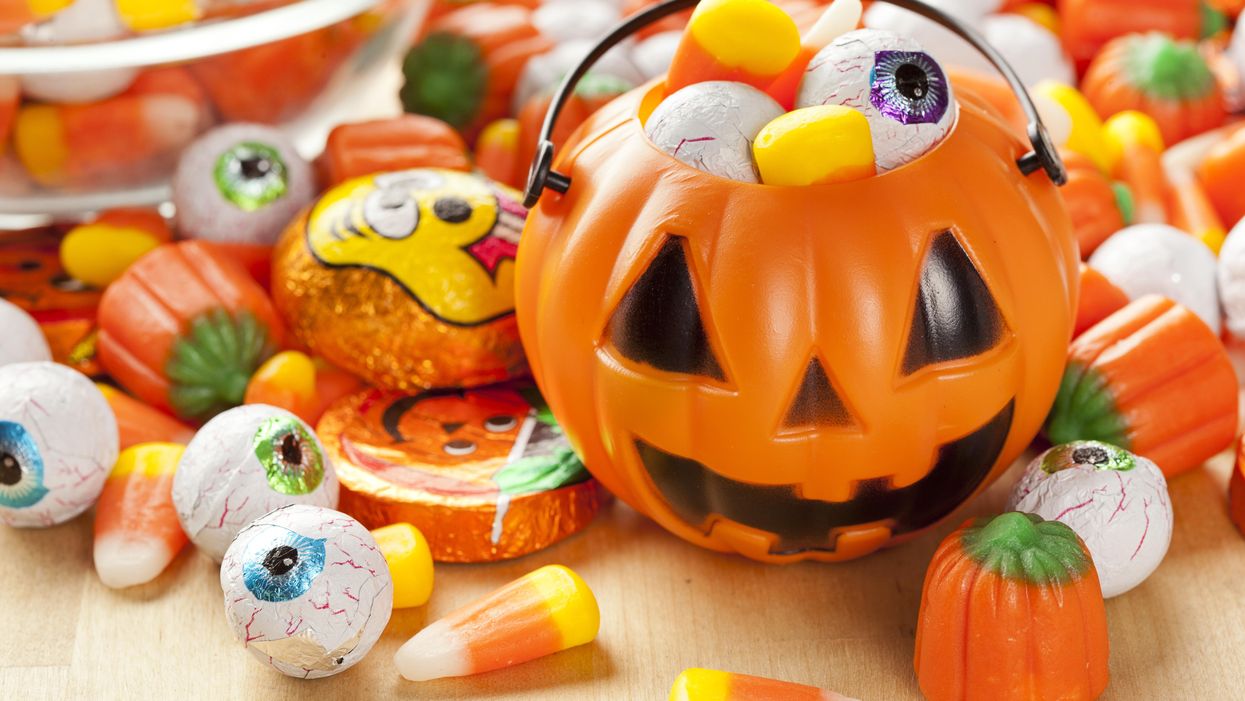 A Halloween pumpkin candy dish filled with candy corn, chocolate pumpkins and chocolate eye balls.