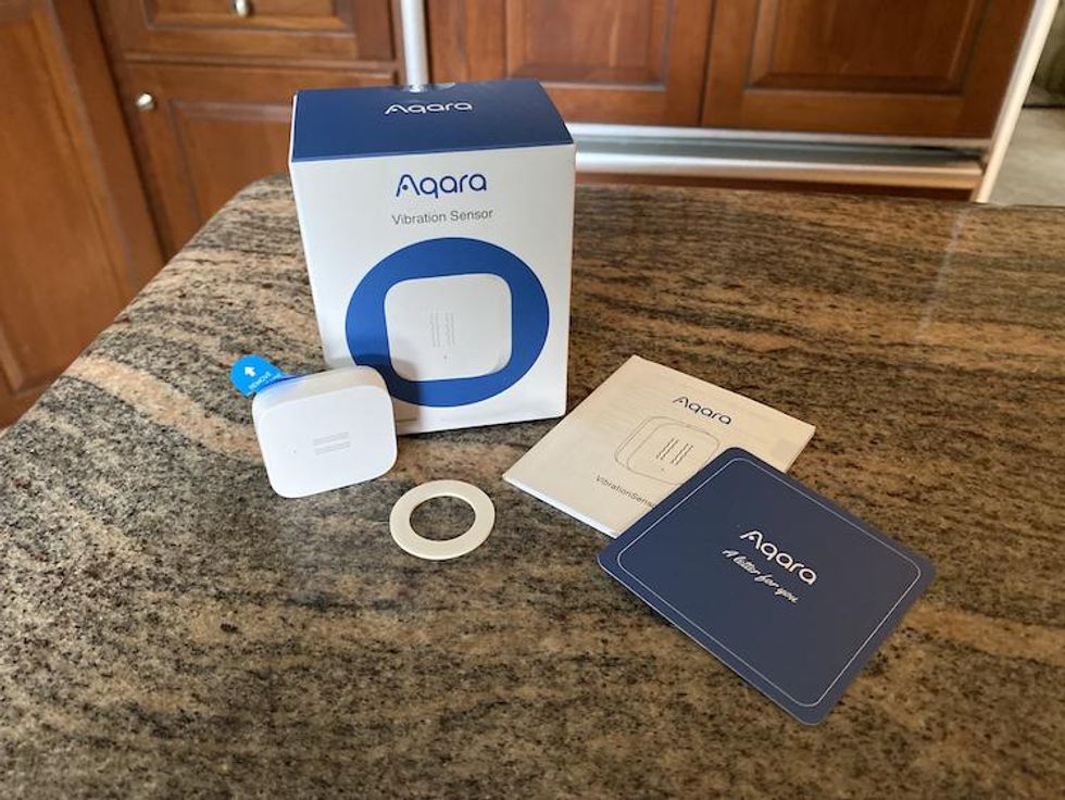 Aqara Vibration Sensor unboxed on a countertop.