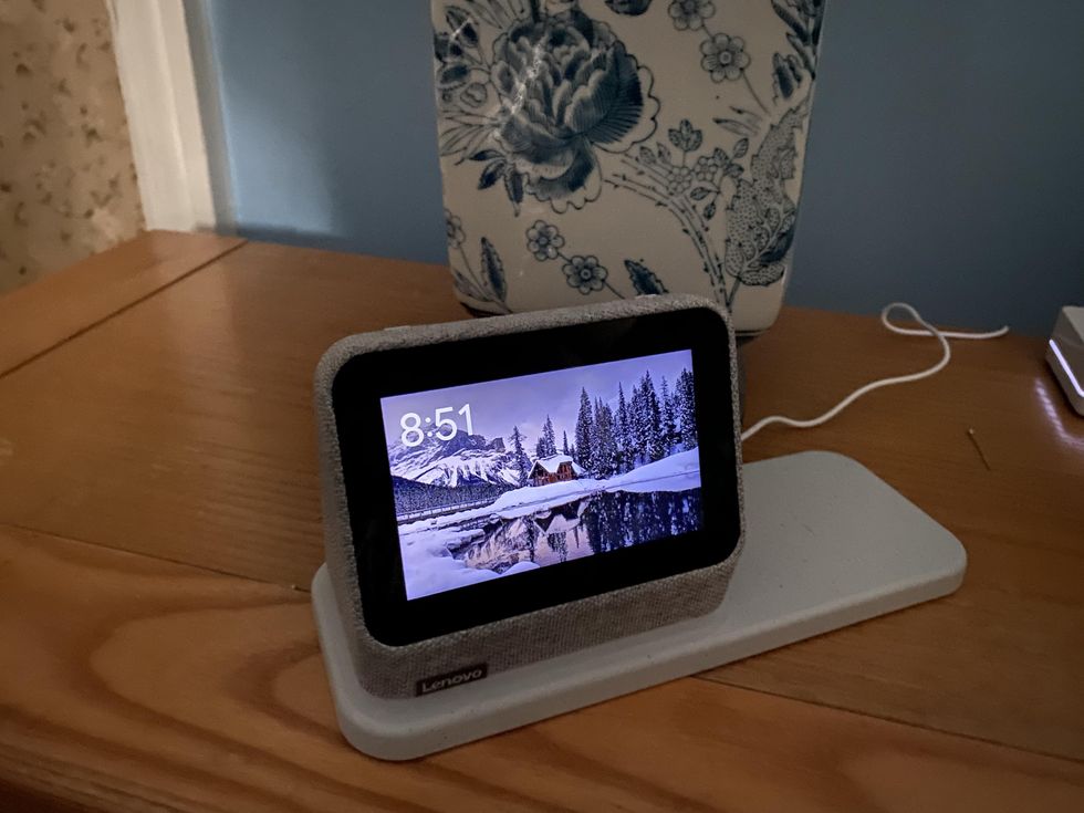 a photo of Lenovo Smart Clock 2 with wireless charging station on an end table in a bedroom