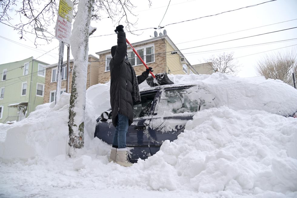 A person digs their car out of snow.