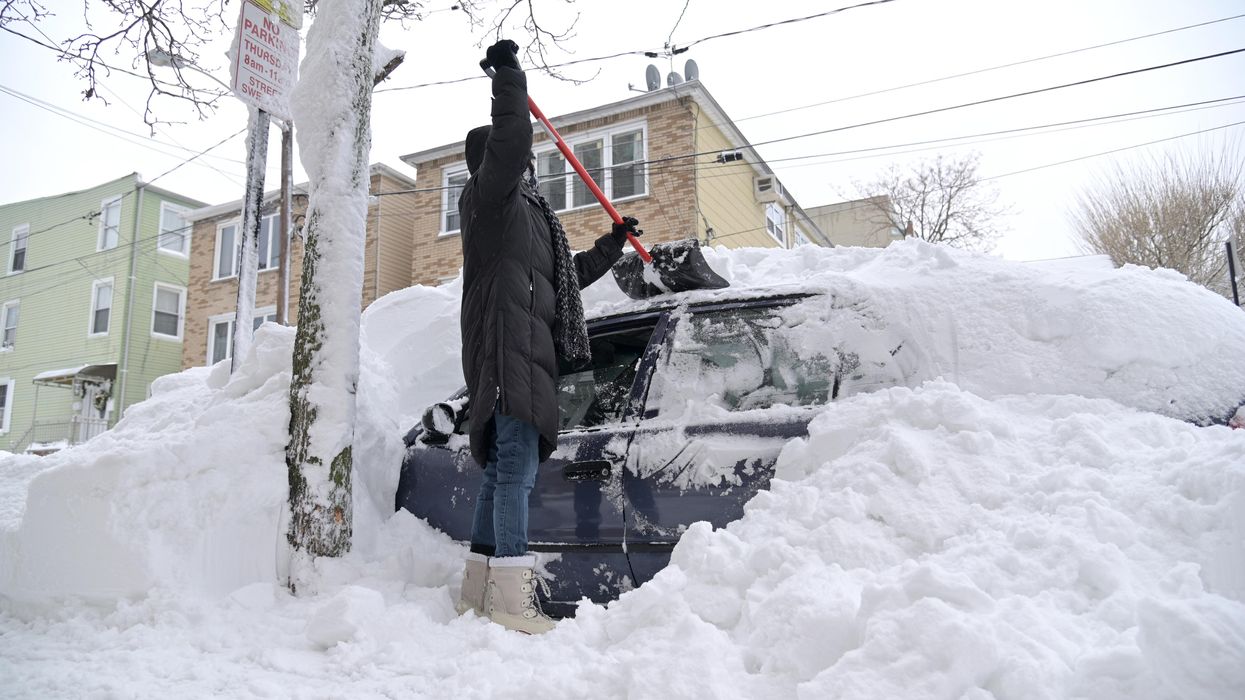 A person digs their car out of snow.
