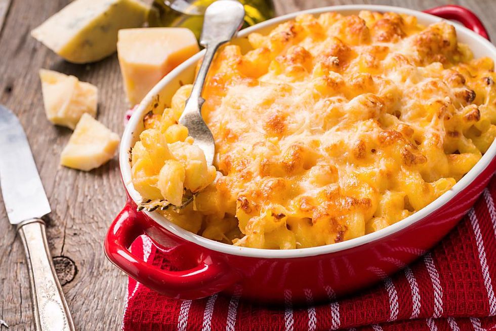 A red pot of baked mac and cheese sitting on a towel on a table.